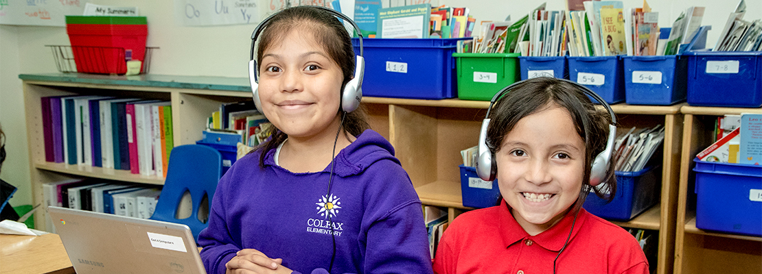 Two Colfax Elementary students with headphones on learning in the classroom